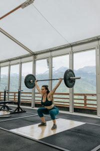 pexels-photo-4943914-4943914 Adult woman lifting weights with mountains visible through gym windows.